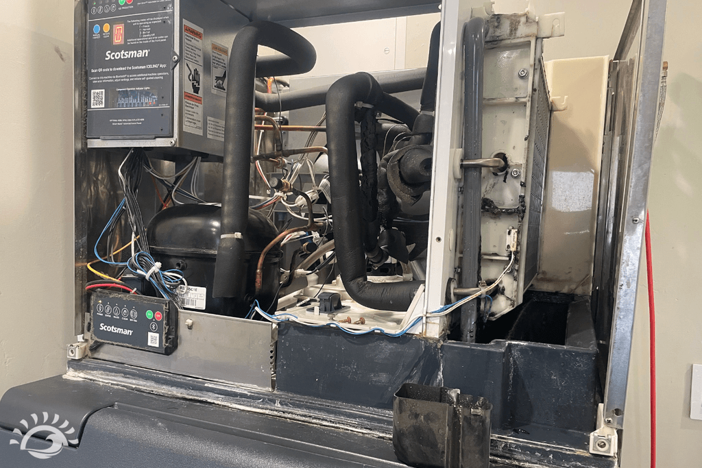 Open Scotsman ice machine showing the compressor and water system during a cleaning